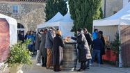 Des barnums blancs abritant les stands de producteurs dans la cour de Domaine Arton en 2023, avec des personnes en train de visiter et déguster